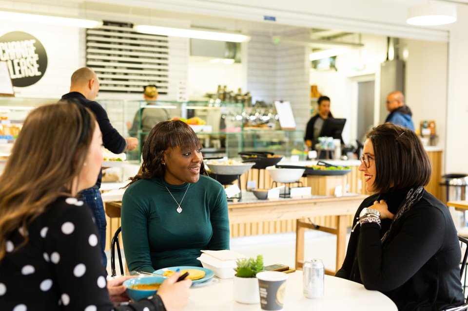 Three people sat around a coffee table, talking and drinking coffee in in the cafe