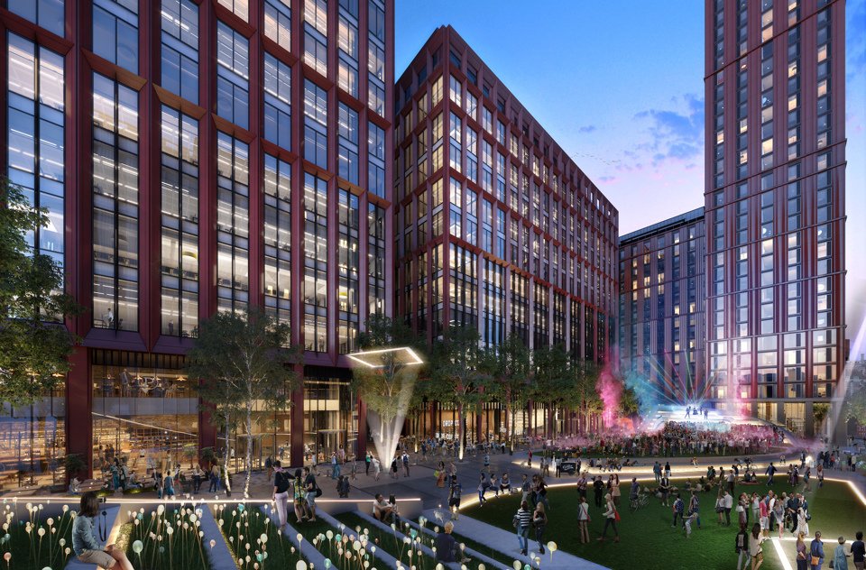 Exterior shot of Circle Square lit up at dusk with groups of people congregating on the grass and surrounding area.