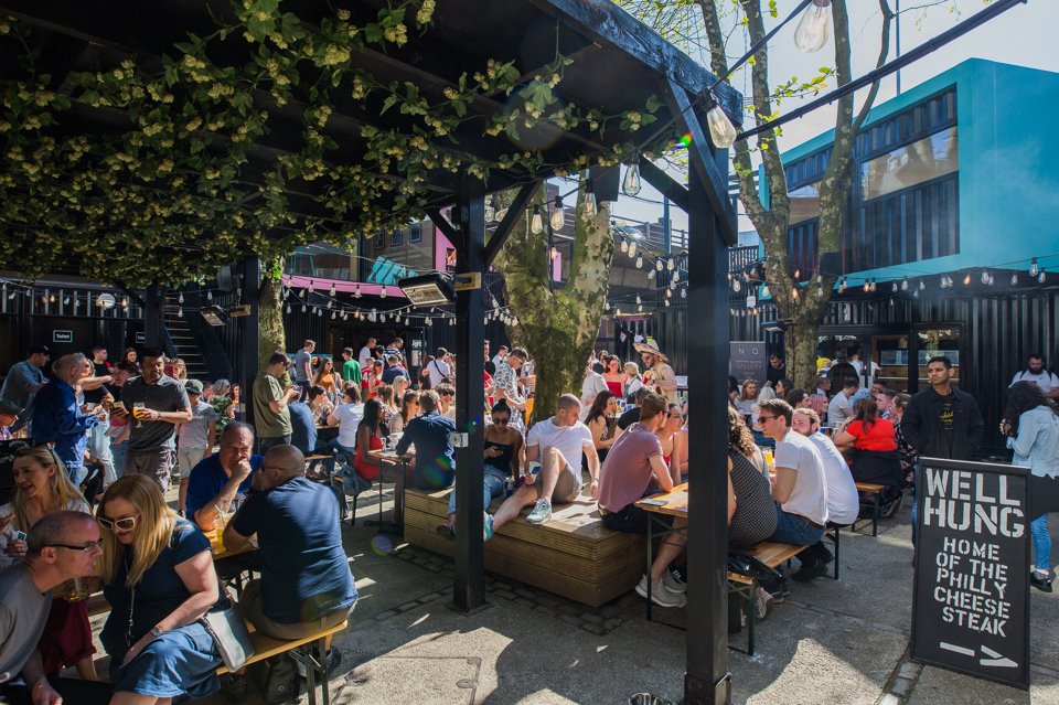 Groups of people socialising in the sun in an urban beer garden