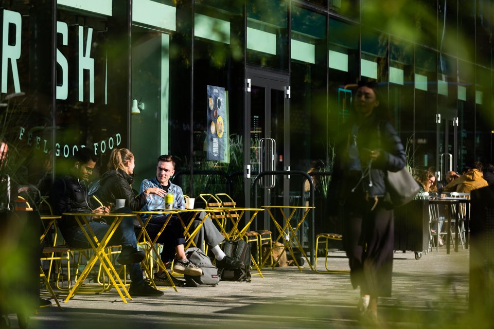 Three people sat outside of Friska enjoying their coffee in the sunshine whilst chatting