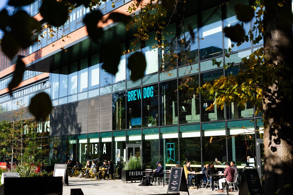 Exterior shot of people sat out Friska and BrewDog enjoying the sunshine