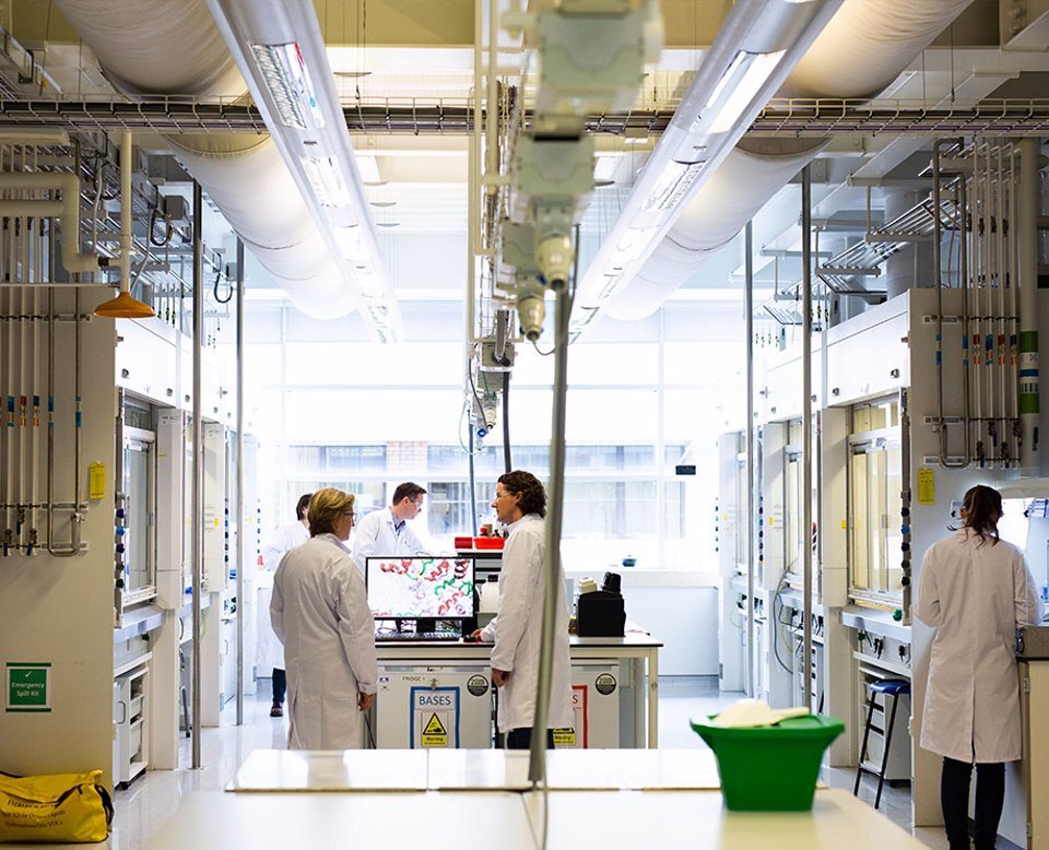 Two people in lab coats working on a computer at the Alderley Park lab space