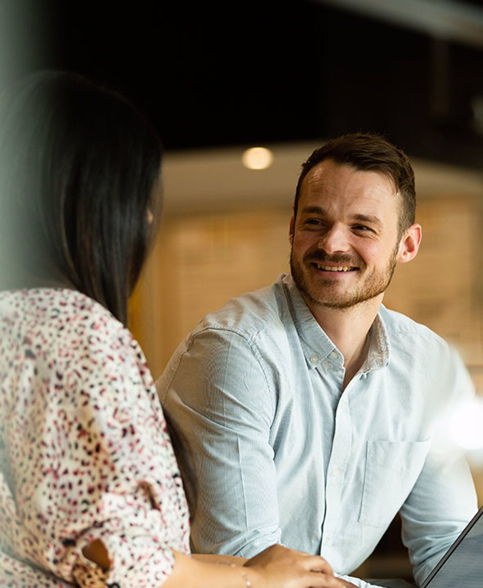 A man and a woman smiling and having a discussion