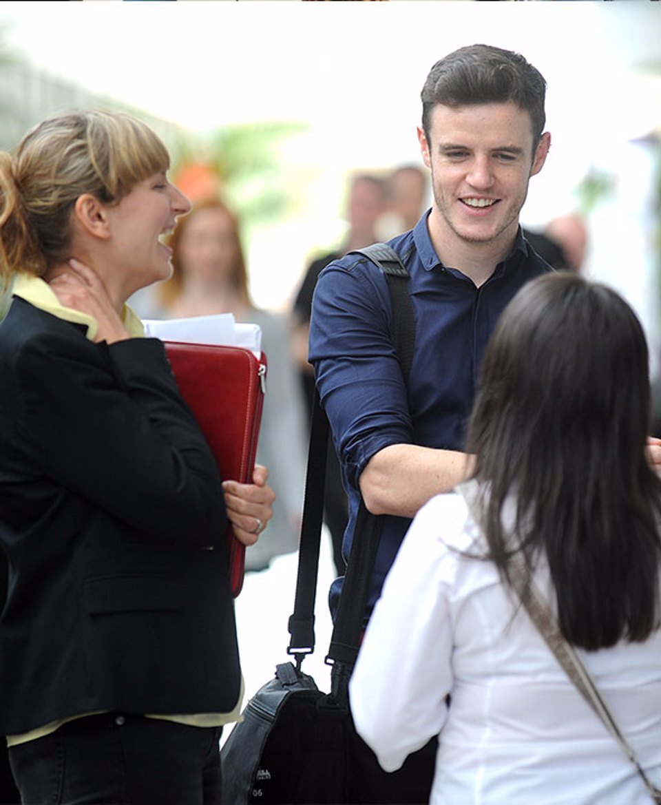 A man and two women smiling and having a discussion