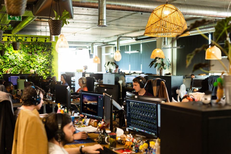 Group of people sat at a desk working on a computer while wearing headphones