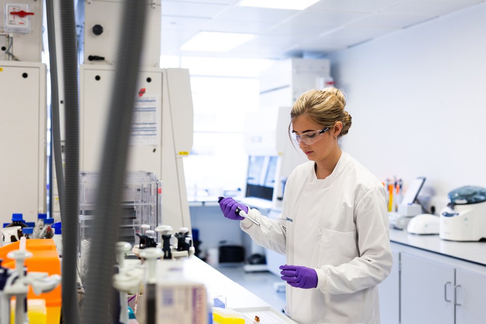 Scientist stood at a desk and working in a lab space