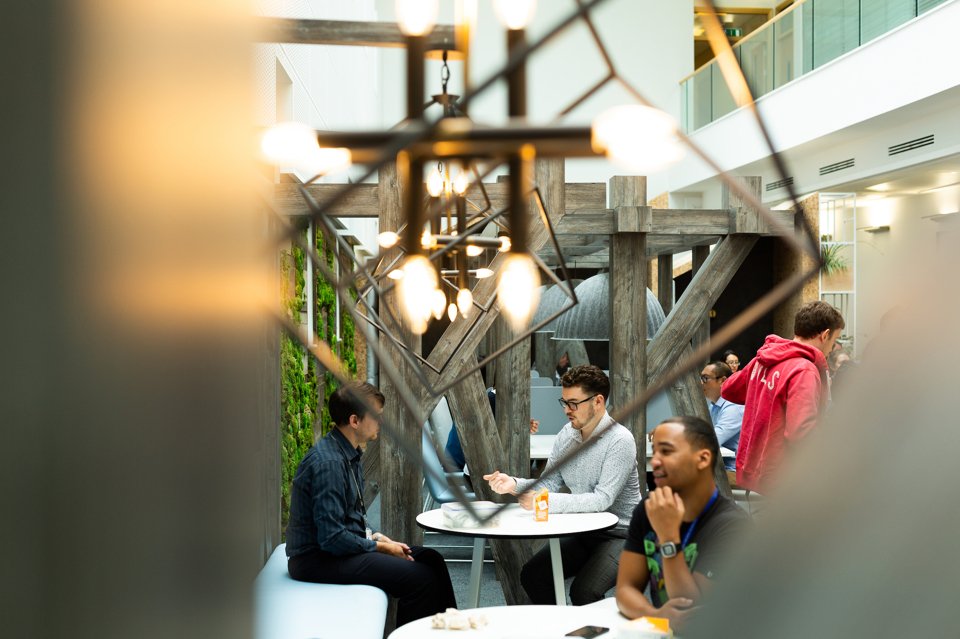 A group of 3 people sat down smiling, having a conversation over lunch