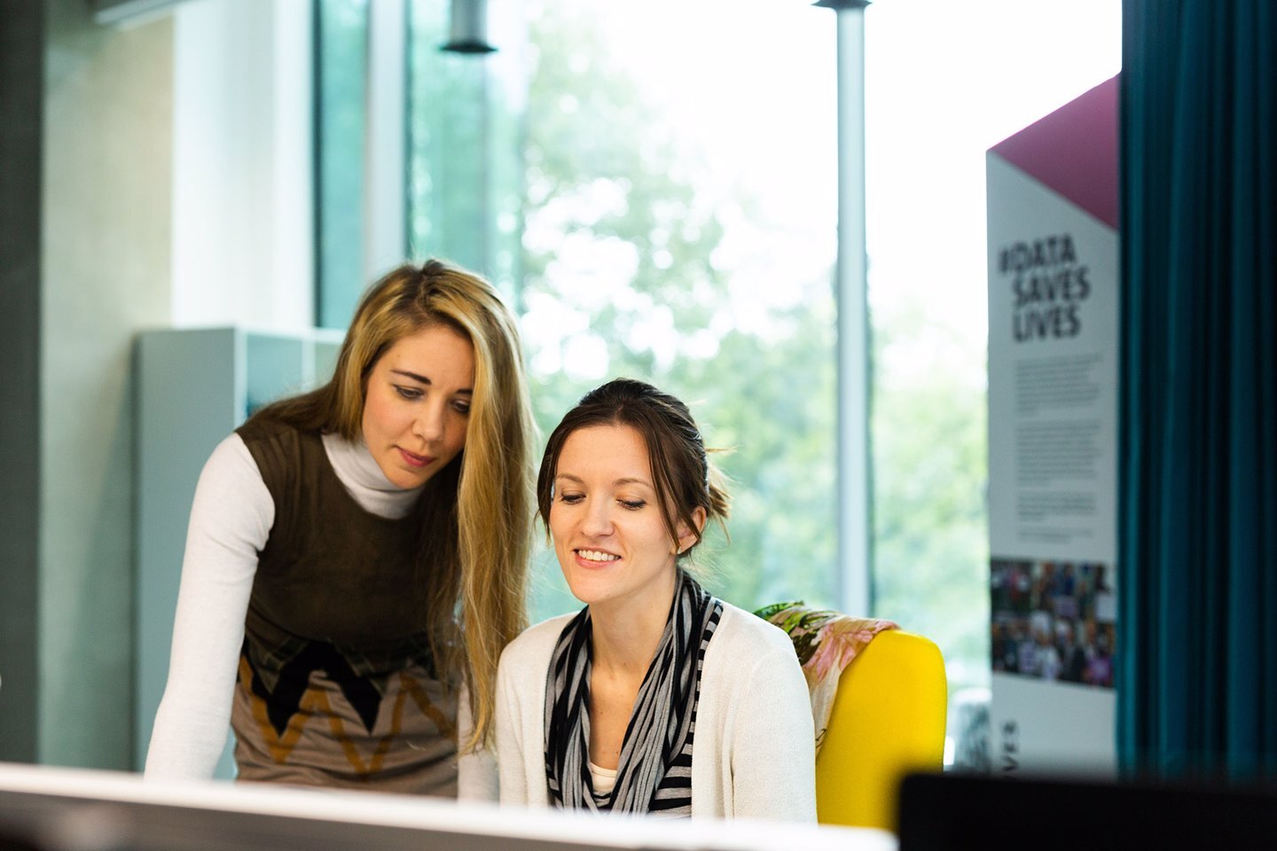 Two women having a discussion looking down at a screen