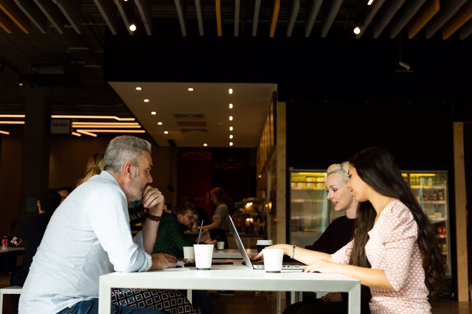 Two women and a man sit around a table having a discussion