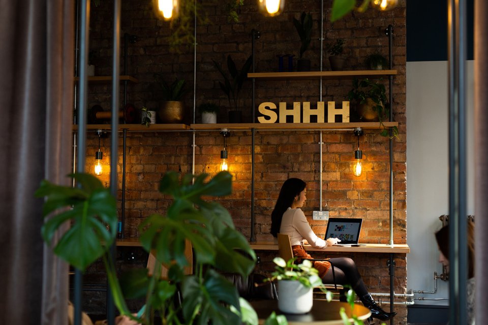 Person sat at a high desk while working on a laptop