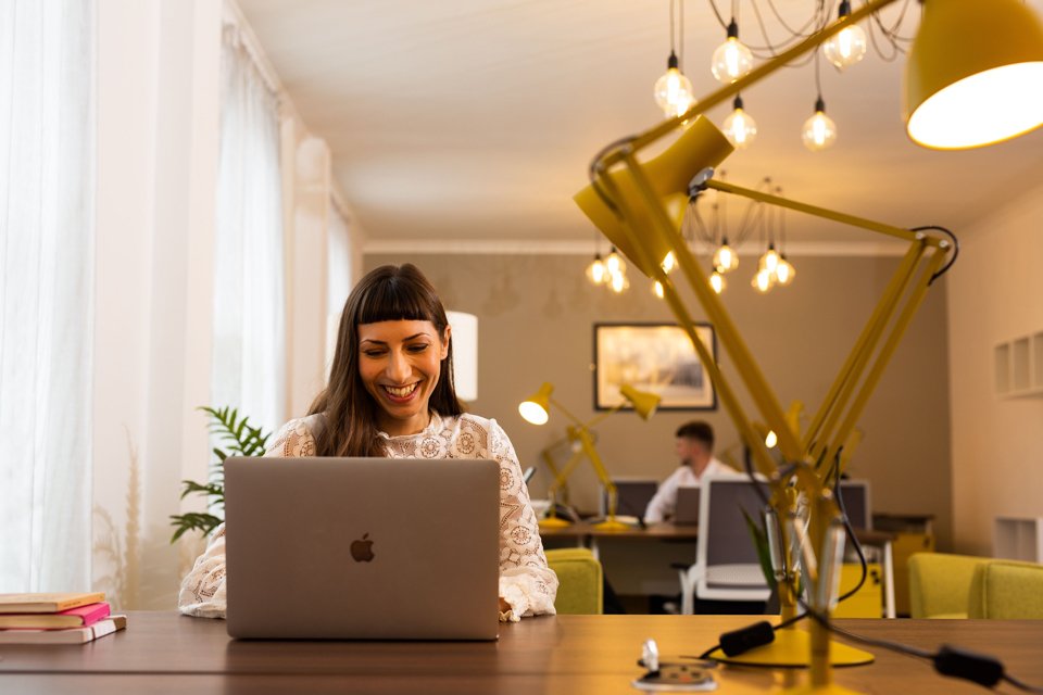 Person smiling while sat at a desk with a laptop