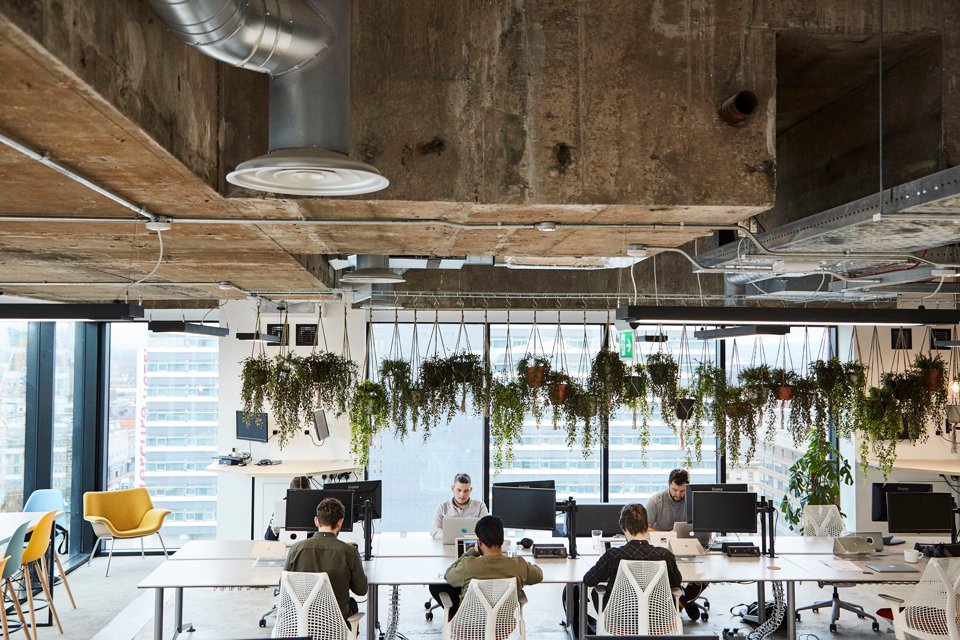 Group of people working side-by-side at wide office desk in office space