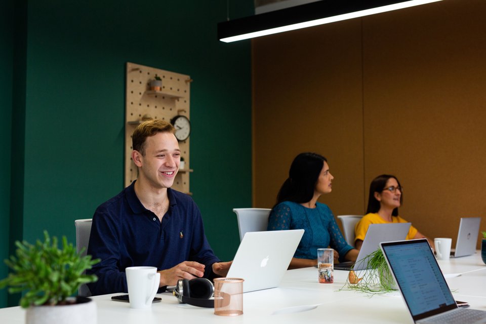 Group of people working side-by-side on laptops at office space desk