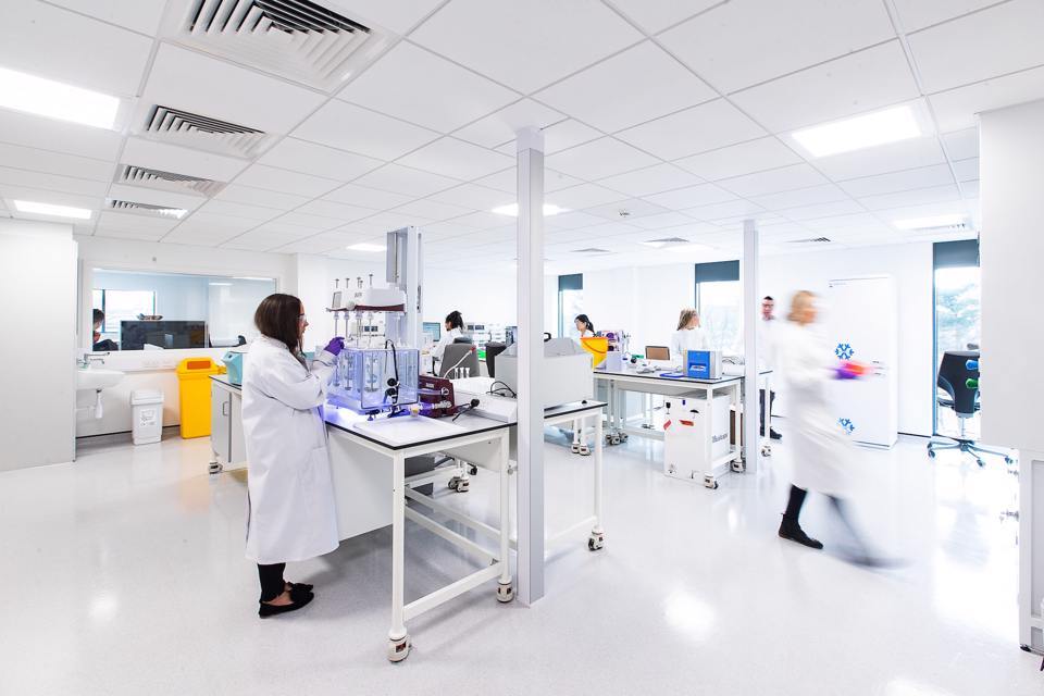 People in lab coats working in a white room at the Alderlaey Park lab space