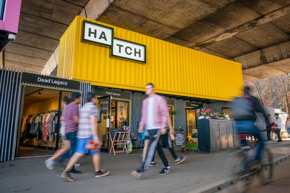 People walking past Hatch shopping attraction on Oxford Road Manchester