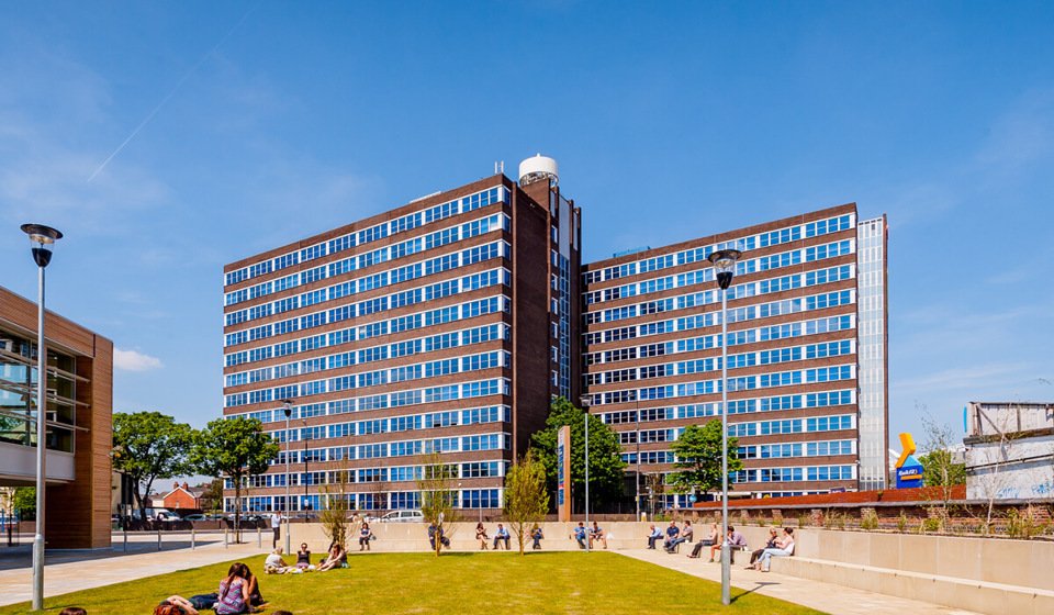 Outside view of Trafford House with people sunbathing in the courtyard.