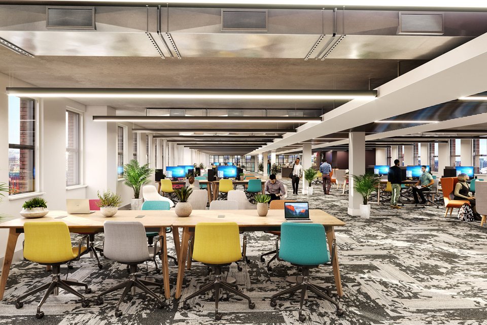 Inside look at large office space inside the west gate building with people sat at office desks working on laptops and computers