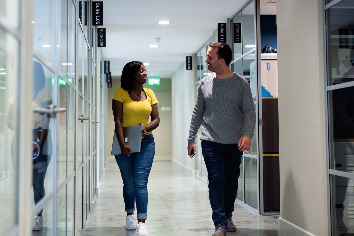 Man and a woman having a discussion walking down a corridor