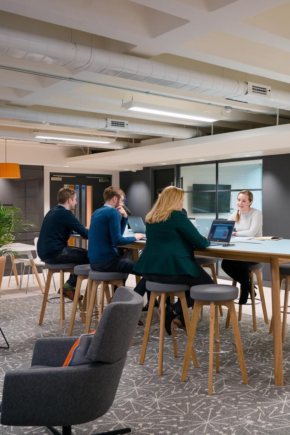 A group of people coworking on a high table in a large open area at 111 piccadilly